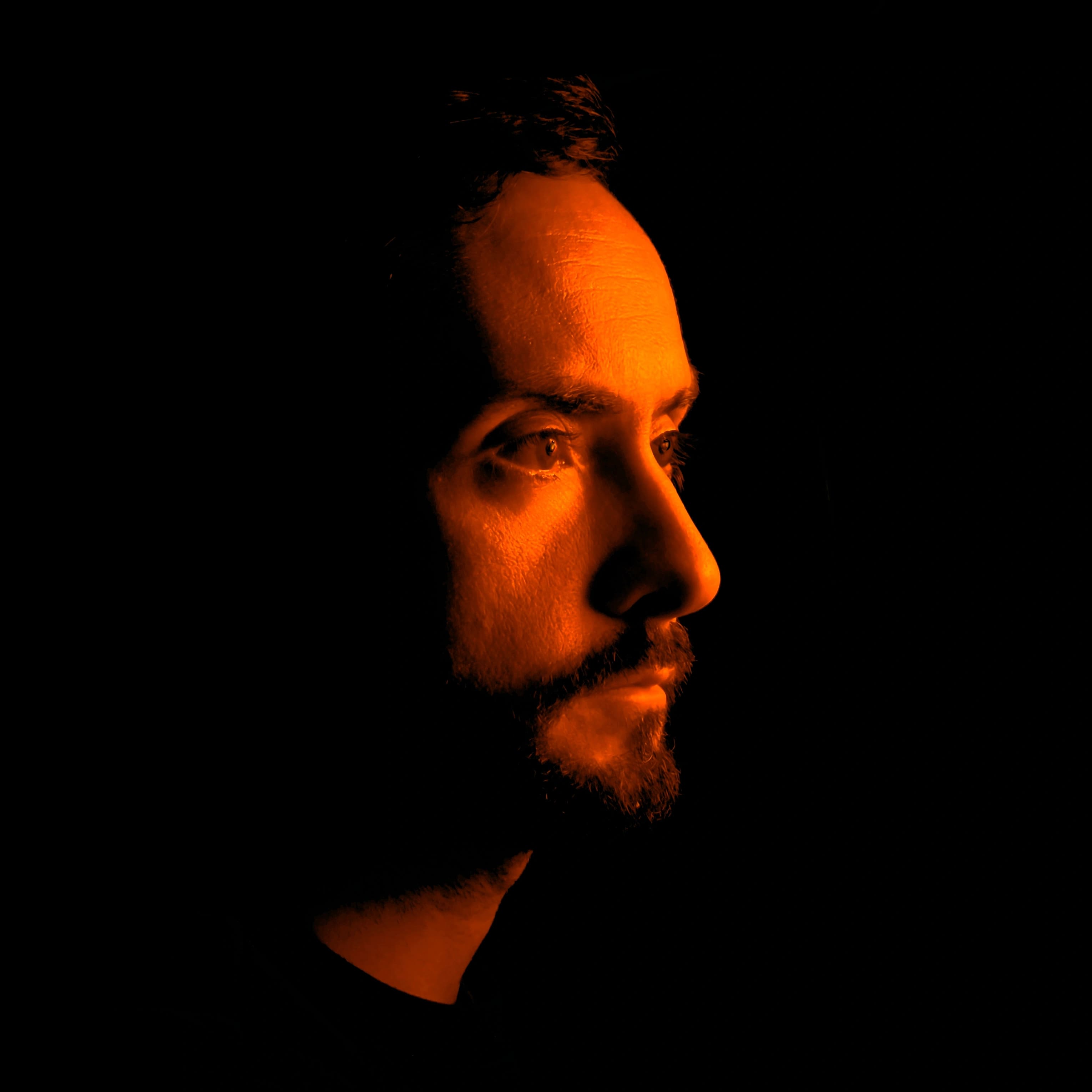 Aleksandar Šterijev in profile, his face lit in orange against a black background