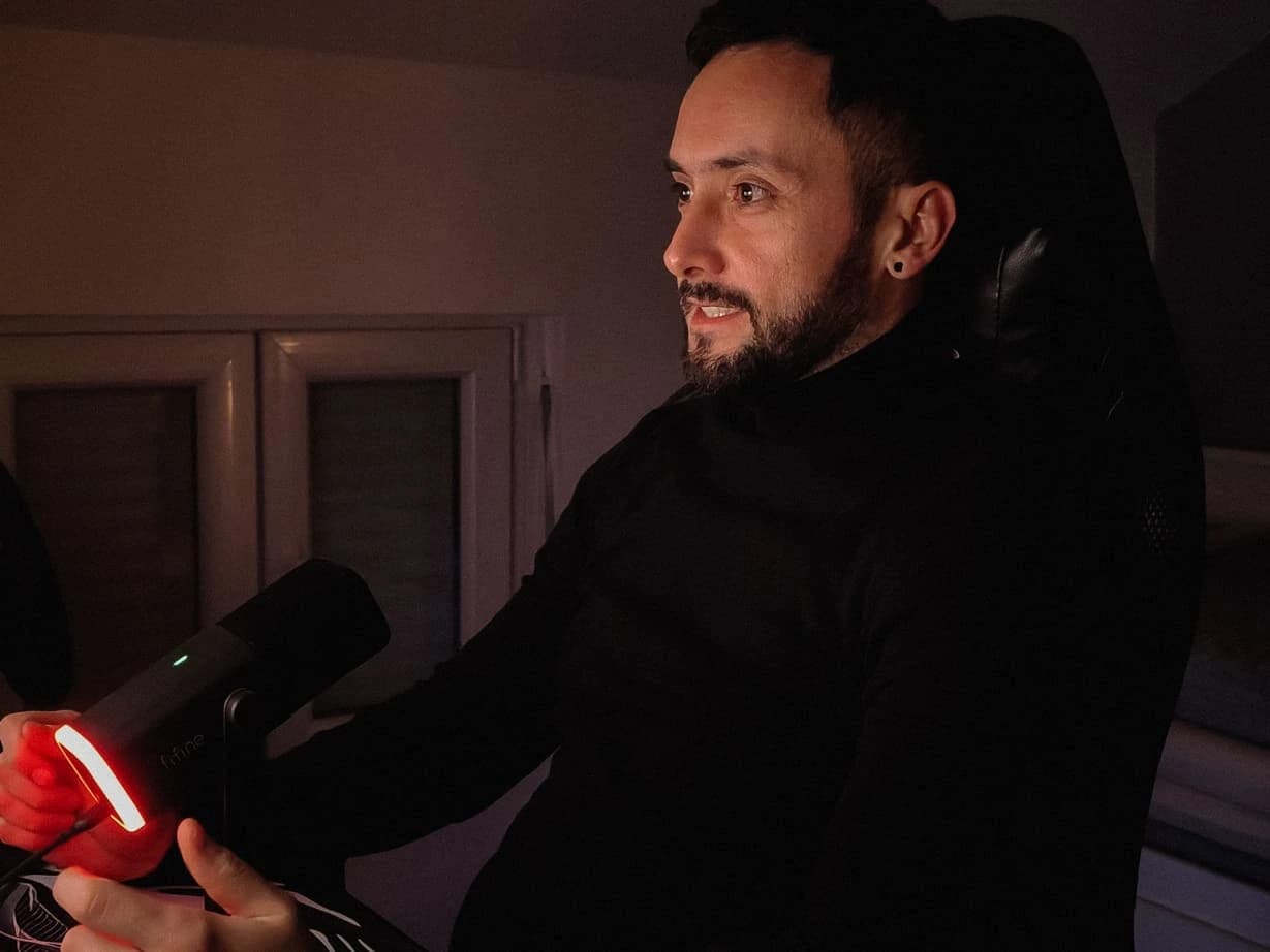 Aleksandar Šterijev at his desk in a dark room, the red ring of a microphone light in the foreground