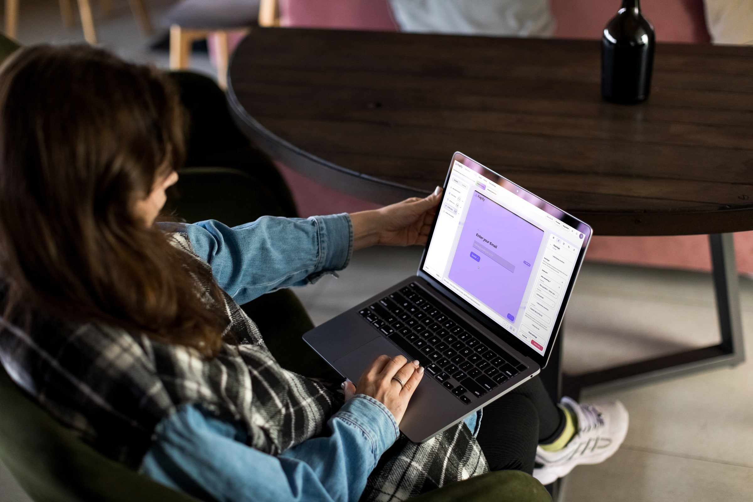 Žena u fotelji uređuje Kaptly formu na laptopu, sa otvorenim panelom za logiku polja