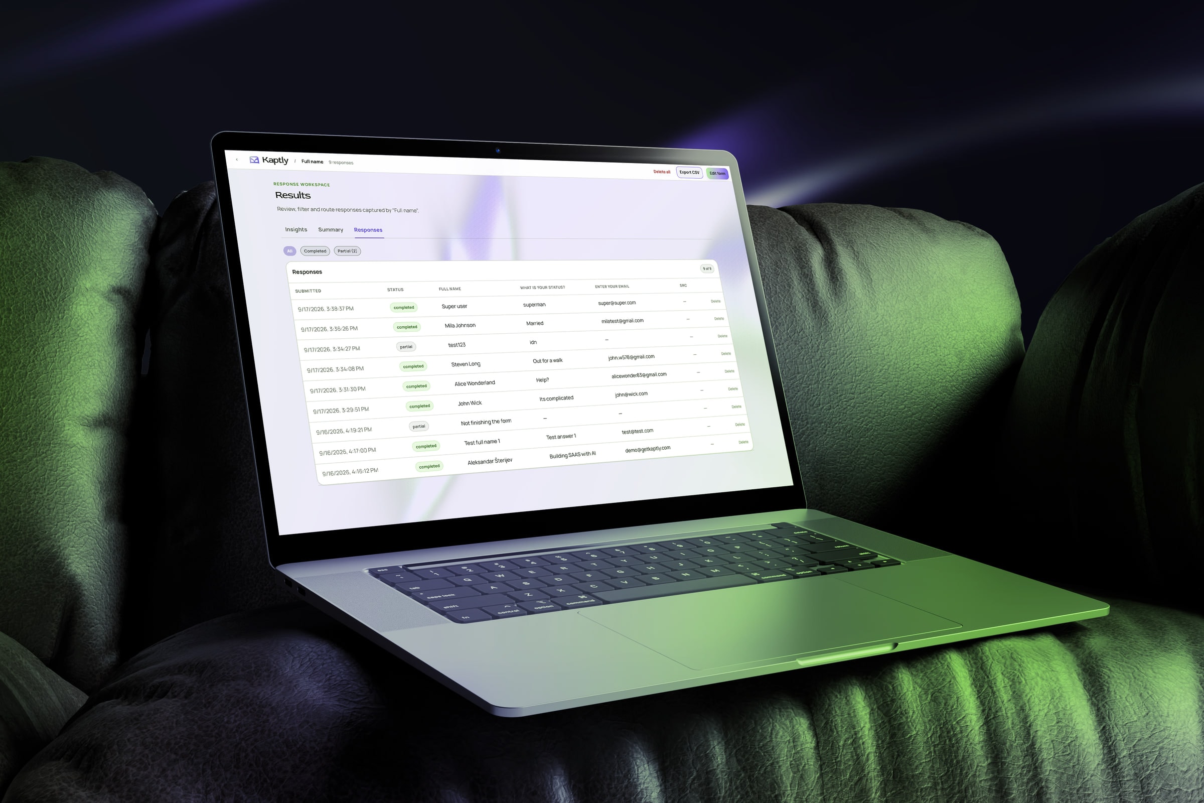 Laptop na sofi u zelenom svetlu prikazuje Kaptly tabelu odgovora sa završenim i delimičnim prijavama